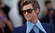 A man wears sunglasses and a shirt with a large collar.