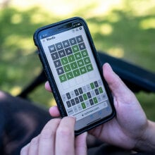 A person sits in their garden playing Wordle.