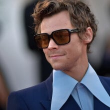 A man wears sunglasses and a shirt with a large collar.