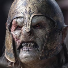 An orc in a helmet snarls and bears its teeth.